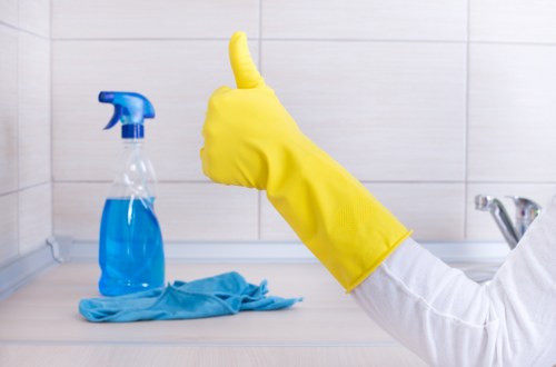 Professional cleaner removing grease and burnt-on residue from a Surrey oven